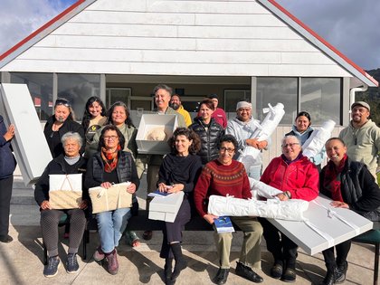 A group of archivists and kaitiaki holding items outside a marae