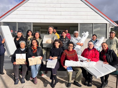 A group of archivists and kaitiaki holding items outside a marae